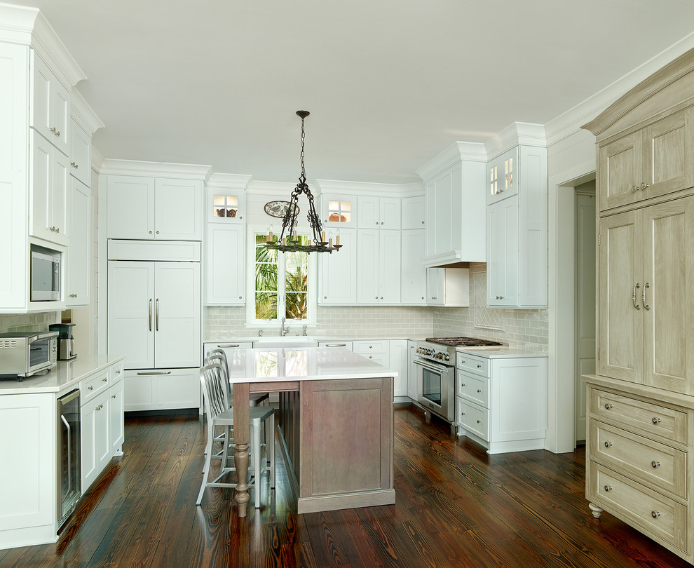 Exempel på ett mellanstort klassiskt kök, med en rustik diskho, vita skåp, bänkskiva i kvarts, grått stänkskydd, stänkskydd i glaskakel, integrerade vitvaror, mörkt trägolv och en köksö