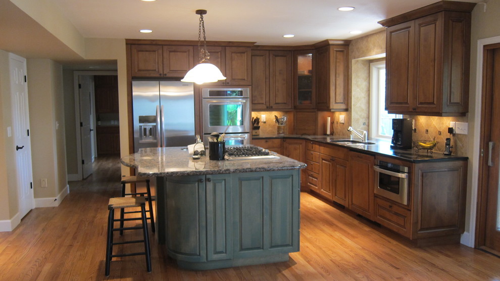Eat-in kitchen - large traditional l-shaped light wood floor eat-in kitchen idea in Denver with an undermount sink, raised-panel cabinets, dark wood cabinets, granite countertops, beige backsplash, ceramic backsplash and stainless steel appliances