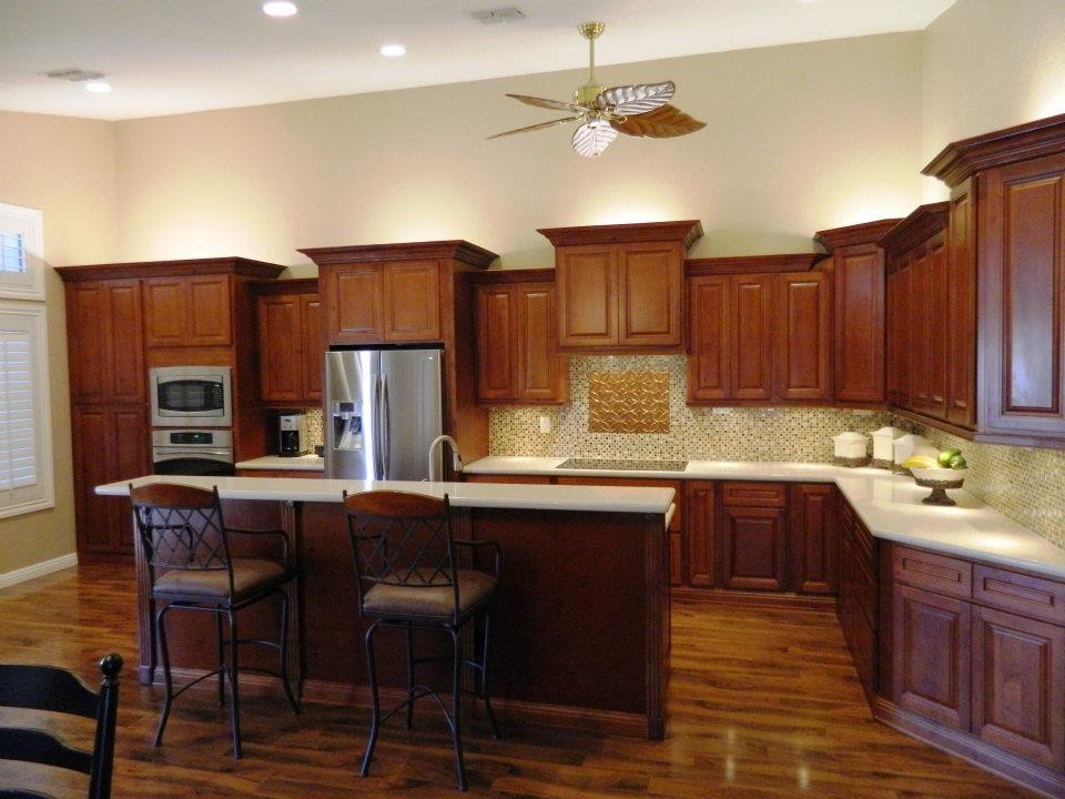 Foto på ett mellanstort vintage kök, med en undermonterad diskho, luckor med upphöjd panel, skåp i mellenmörkt trä, bänkskiva i kvartsit, beige stänkskydd, stänkskydd i keramik, rostfria vitvaror, en köksö, mellanmörkt trägolv och brunt golv
