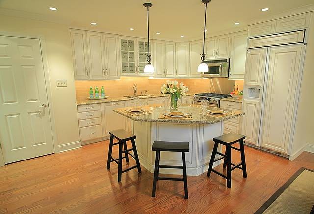 Mid-sized elegant l-shaped medium tone wood floor and brown floor eat-in kitchen photo in Philadelphia with an undermount sink, raised-panel cabinets, light wood cabinets, granite countertops, brown backsplash, paneled appliances and an island