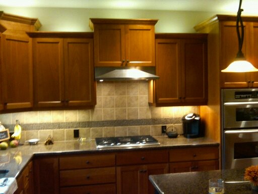 Immagine di una cucina stile americano con ante lisce, ante in legno bruno, top in granito, paraspruzzi beige, paraspruzzi con piastrelle in ceramica e elettrodomestici in acciaio inossidabile