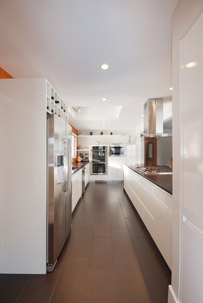 Imagen de cocina contemporánea con electrodomésticos de acero inoxidable, armarios con paneles lisos, puertas de armario blancas y encimera de cuarzo compacto