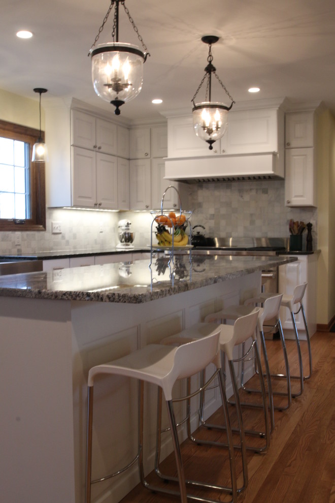 Inredning av ett lantligt stort kök, med en rustik diskho, luckor med upphöjd panel, vita skåp, granitbänkskiva, vitt stänkskydd, stänkskydd i marmor, rostfria vitvaror, ljust trägolv, en köksö och brunt golv