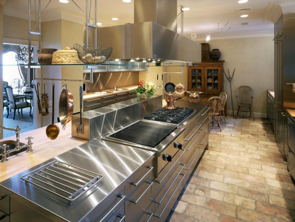 Immagine di una grande cucina industriale con lavello da incasso, ante con bugna sagomata, ante grigie, top in legno, elettrodomestici in acciaio inossidabile e pavimento in gres porcellanato