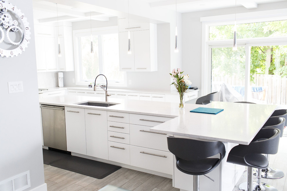 Inspiration for a mid-sized contemporary u-shaped ceramic tile and gray floor kitchen remodel in Ottawa with an undermount sink, flat-panel cabinets, white cabinets, quartz countertops, white backsplash, stainless steel appliances, an island and white countertops