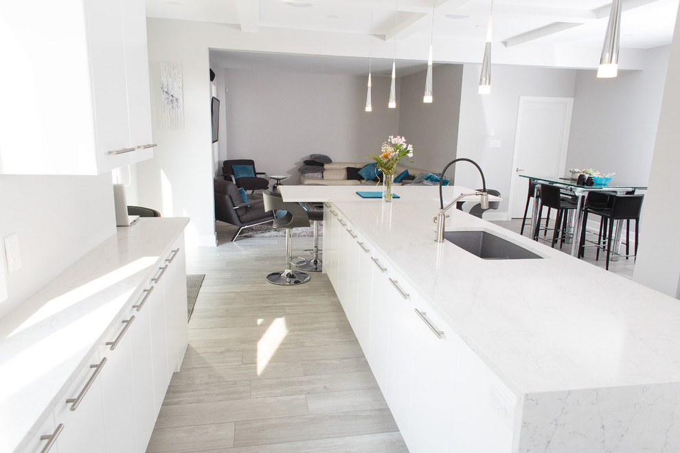 Example of a mid-sized trendy u-shaped ceramic tile and gray floor kitchen design in Ottawa with an undermount sink, flat-panel cabinets, white cabinets, quartz countertops, white backsplash, stainless steel appliances, an island and white countertops