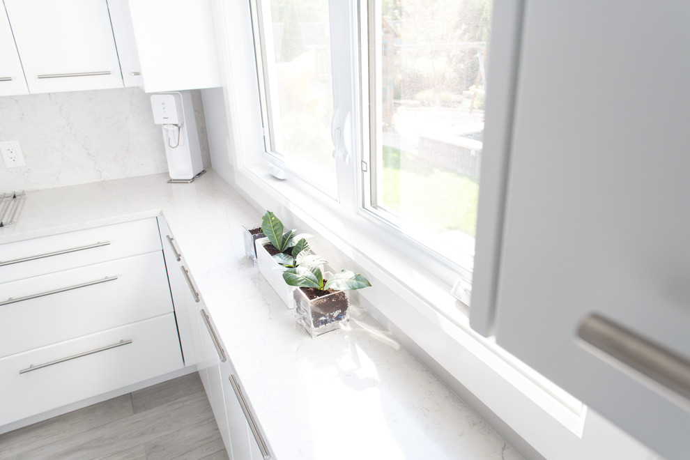 Kitchen - mid-sized contemporary u-shaped ceramic tile and gray floor kitchen idea in Ottawa with an undermount sink, flat-panel cabinets, white cabinets, quartz countertops, white backsplash, stainless steel appliances, an island and white countertops