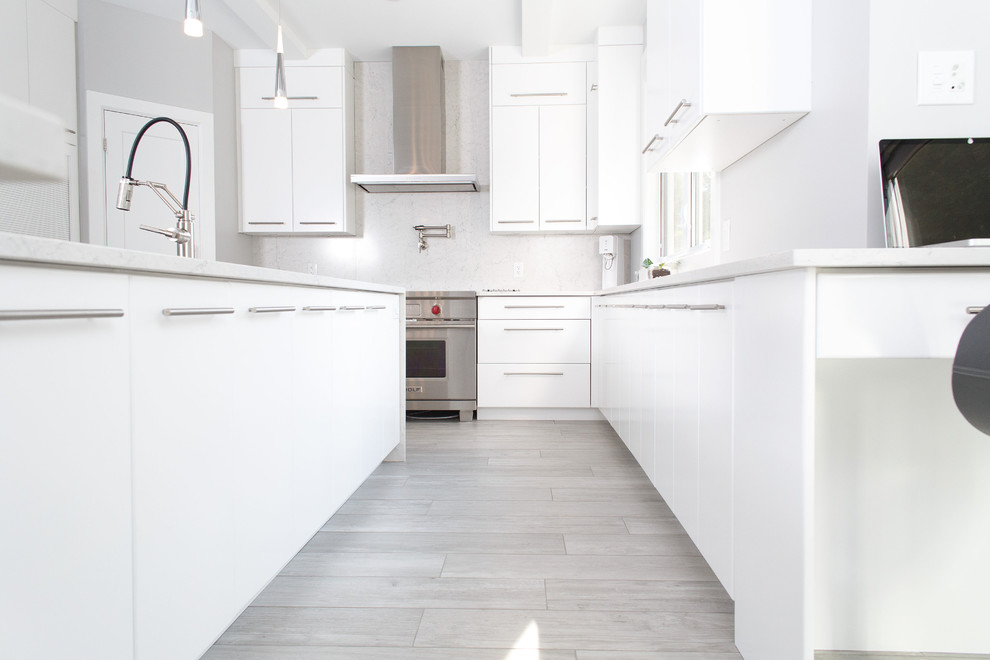 Example of a mid-sized trendy u-shaped ceramic tile and gray floor kitchen design in Ottawa with an undermount sink, flat-panel cabinets, white cabinets, quartz countertops, white backsplash, stainless steel appliances, an island and white countertops