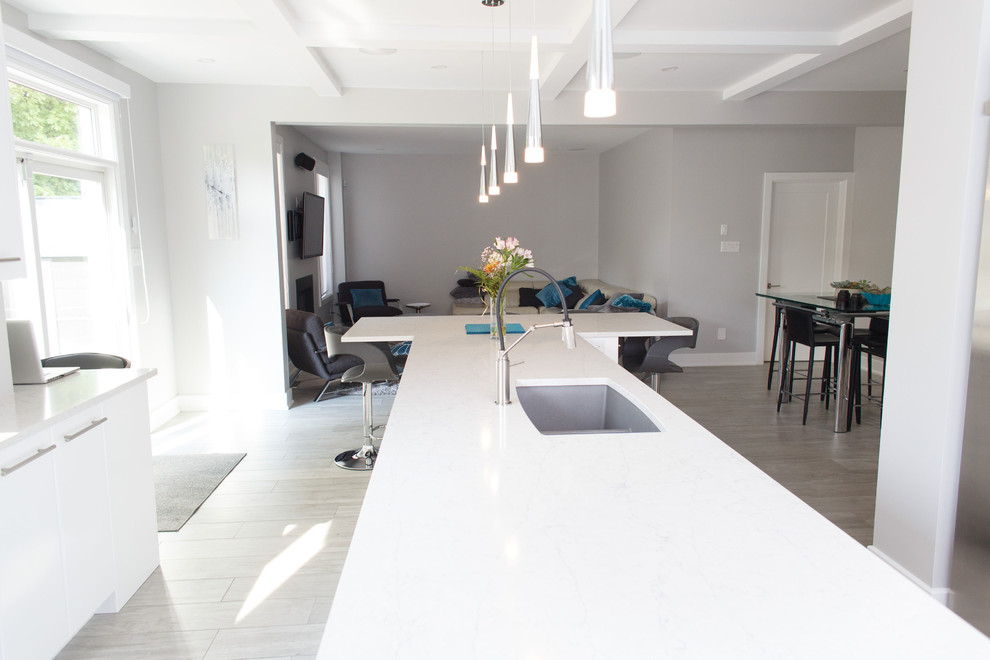 Inspiration for a mid-sized contemporary u-shaped ceramic tile and gray floor kitchen remodel in Ottawa with an undermount sink, flat-panel cabinets, white cabinets, quartz countertops, white backsplash, stainless steel appliances, an island and white countertops