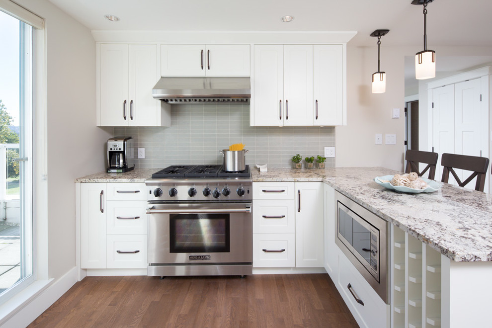 Inspiration for a mid-sized transitional l-shaped medium tone wood floor and brown floor eat-in kitchen remodel in Other with an undermount sink, shaker cabinets, white cabinets, granite countertops, gray backsplash, stainless steel appliances and a peninsula