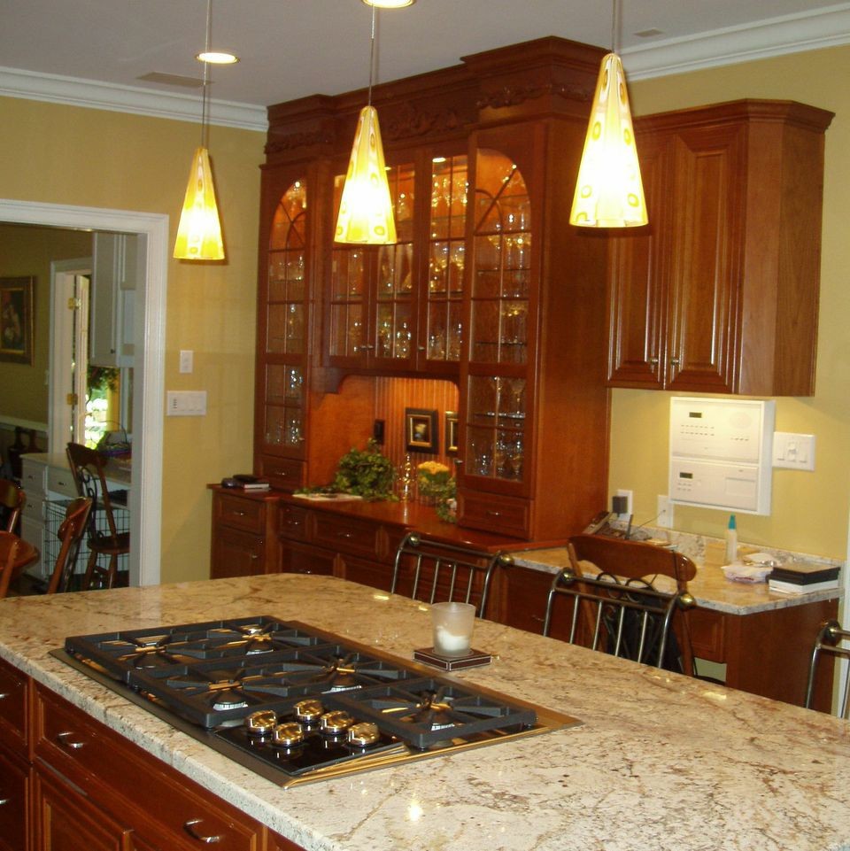 Photo of a large traditional l-shaped open plan kitchen in Atlanta with a belfast sink, raised-panel cabinets, medium wood cabinets, granite worktops, yellow splashback, stainless steel appliances, medium hardwood flooring and an island.