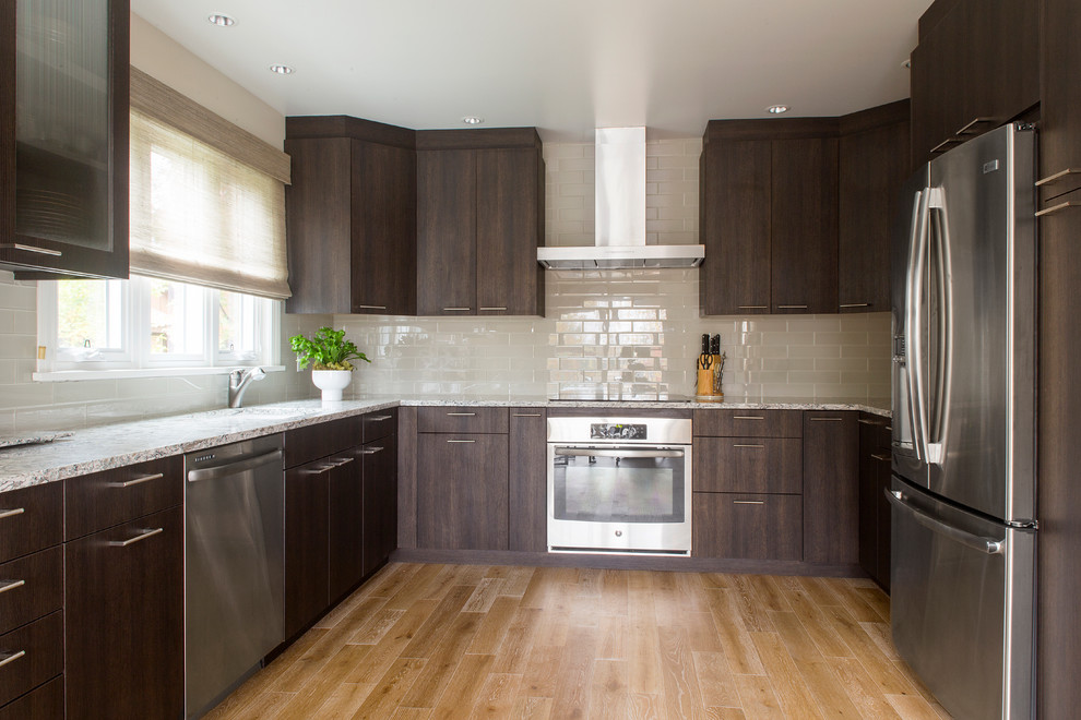 Example of a trendy medium tone wood floor kitchen design in New York with an undermount sink, flat-panel cabinets, quartzite countertops, glass tile backsplash and stainless steel appliances