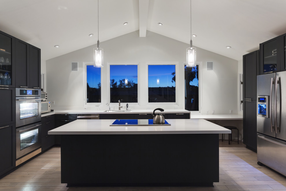 Foto di una grande cucina chic con ante lisce, ante nere, top in superficie solida, elettrodomestici in acciaio inossidabile e parquet chiaro