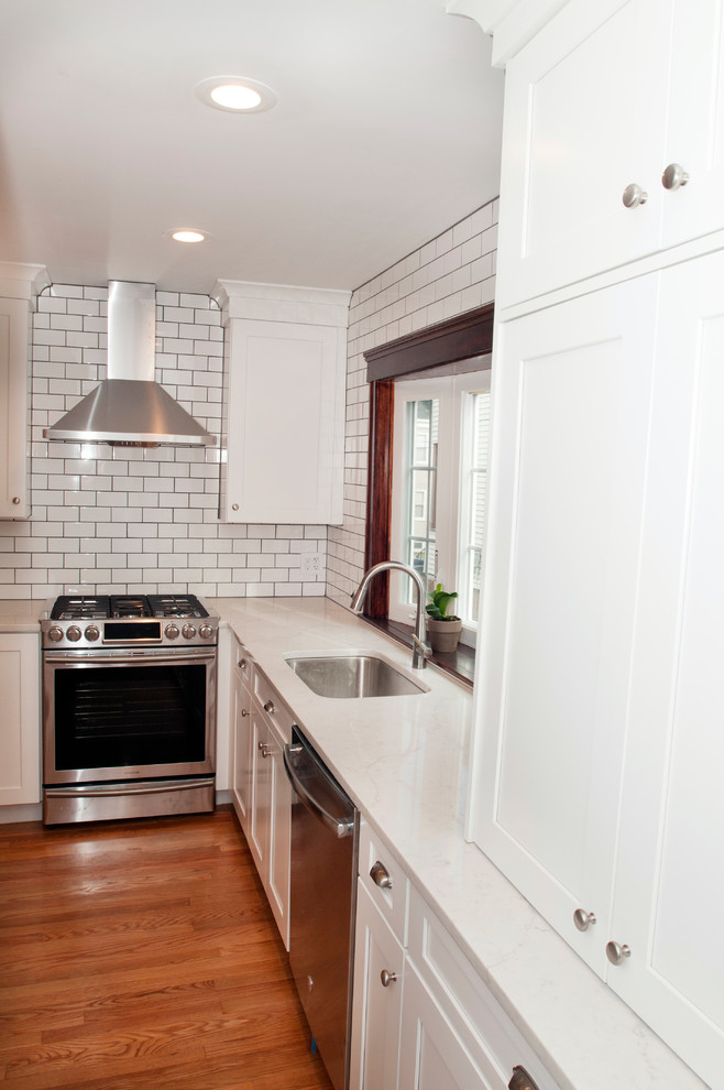 Design ideas for a small classic galley kitchen in Boston with a single-bowl sink, shaker cabinets, white cabinets, quartz worktops, metro tiled splashback, stainless steel appliances, medium hardwood flooring and an island.