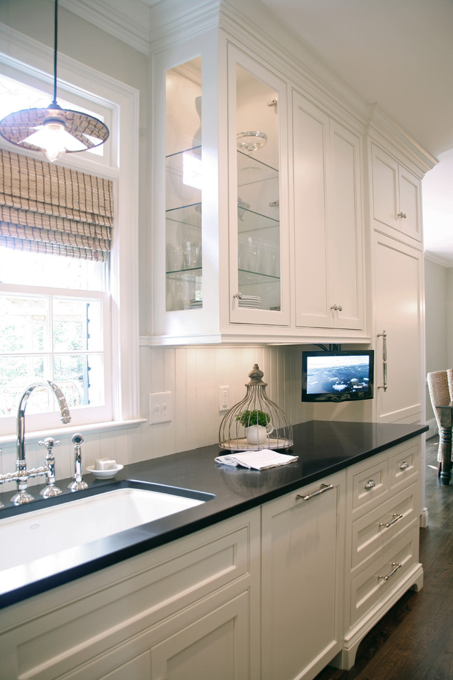 Photo of a large modern u-shaped kitchen pantry in Atlanta with a submerged sink, recessed-panel cabinets, white cabinets, composite countertops, white splashback, integrated appliances, medium hardwood flooring and an island.