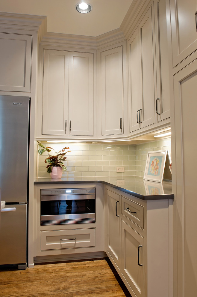 Example of a mid-sized classic l-shaped medium tone wood floor open concept kitchen design in Atlanta with an undermount sink, shaker cabinets, white cabinets, marble countertops, blue backsplash, glass tile backsplash, stainless steel appliances and an island
