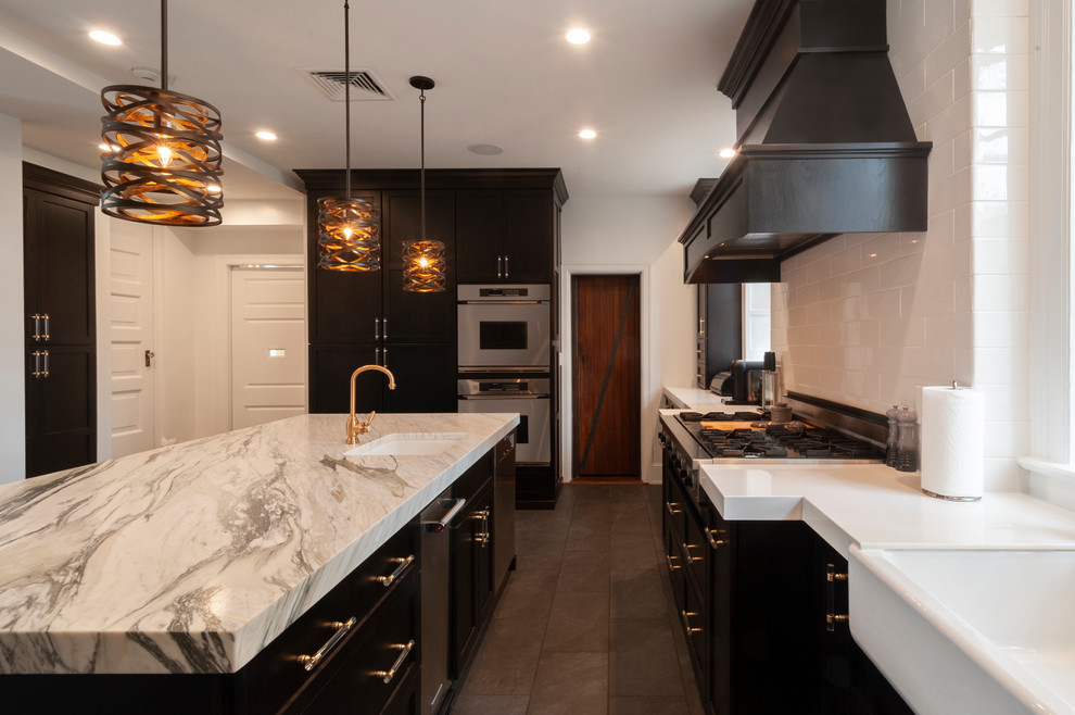 Inspiration for a large transitional u-shaped porcelain tile and black floor eat-in kitchen remodel in Philadelphia with a farmhouse sink, shaker cabinets, black cabinets, marble countertops, white backsplash, subway tile backsplash, stainless steel appliances, an island and white countertops