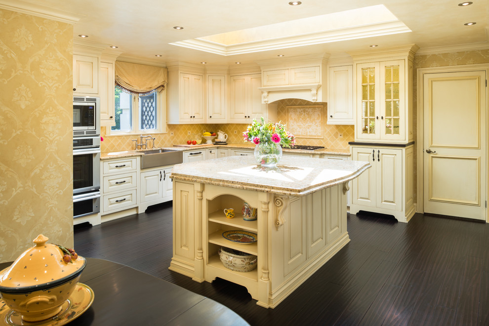 Example of a classic l-shaped eat-in kitchen design in Philadelphia with a farmhouse sink, raised-panel cabinets, yellow cabinets, yellow backsplash, ceramic backsplash, stainless steel appliances and granite countertops
