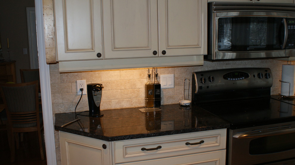 Klassisk inredning av ett avskilt u-kök, med luckor med upphöjd panel, beige skåp, granitbänkskiva, beige stänkskydd, stänkskydd i cementkakel och rostfria vitvaror