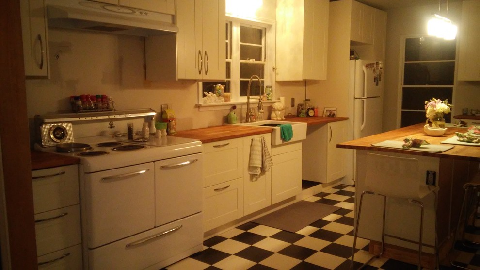 ダラスにある低価格の中くらいなエクレクティックスタイルのおしゃれなキッチン (エプロンフロントシンク、シェーカースタイル扉のキャビネット、白いキャビネット、木材カウンター、白い調理設備) の写真