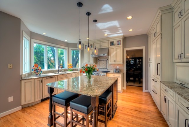 Eat-in kitchen - mid-sized contemporary l-shaped medium tone wood floor eat-in kitchen idea in DC Metro with an undermount sink, recessed-panel cabinets, white cabinets, granite countertops, beige backsplash, stone tile backsplash, paneled appliances and an island