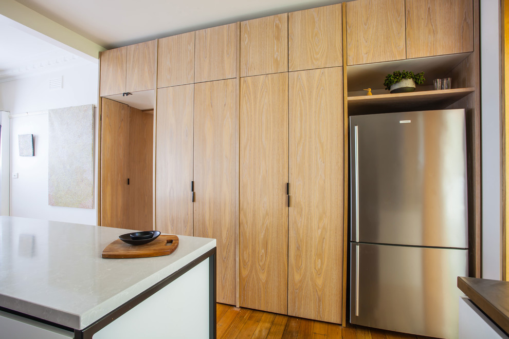 Bild på ett mellanstort funkis kök, med en dubbel diskho, släta luckor, vita skåp, bänkskiva i rostfritt stål, grönt stänkskydd, stänkskydd i keramik, rostfria vitvaror, mellanmörkt trägolv och en köksö