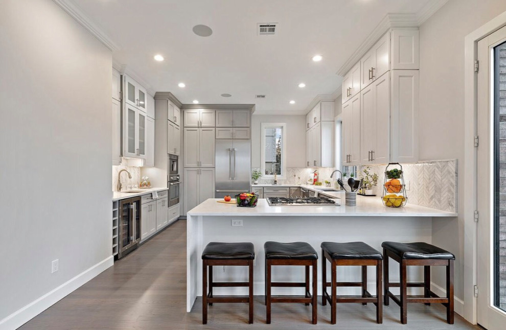 Mid-sized transitional u-shaped dark wood floor and gray floor eat-in kitchen photo in New York with an undermount sink, shaker cabinets, white cabinets, quartzite countertops, multicolored backsplash, marble backsplash, stainless steel appliances, a peninsula and white countertops