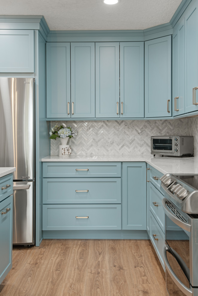 Design ideas for a medium sized contemporary l-shaped kitchen/diner in Tampa with a submerged sink, shaker cabinets, turquoise cabinets, engineered stone countertops, white splashback, marble splashback, stainless steel appliances, vinyl flooring, an island, beige floors and white worktops.