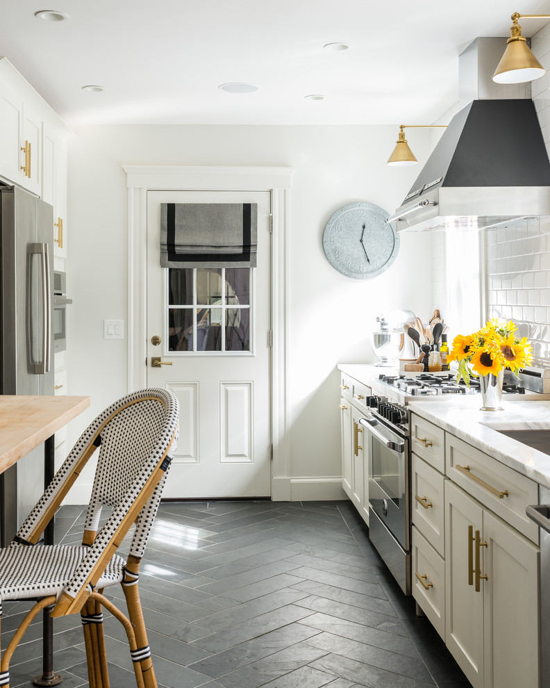 Small minimalist galley slate floor eat-in kitchen photo in Boston with an undermount sink, white cabinets, marble countertops, white backsplash, subway tile backsplash, stainless steel appliances and an island