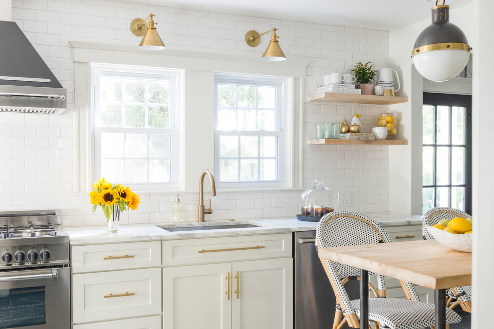 Foto på ett litet funkis kök, med en undermonterad diskho, vita skåp, marmorbänkskiva, vitt stänkskydd, stänkskydd i tunnelbanekakel och rostfria vitvaror