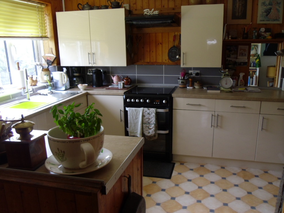 Small classic u-shaped kitchen/diner in Sussex with a single-bowl sink, flat-panel cabinets, white cabinets, laminate countertops, beige splashback, porcelain splashback, white appliances and lino flooring.