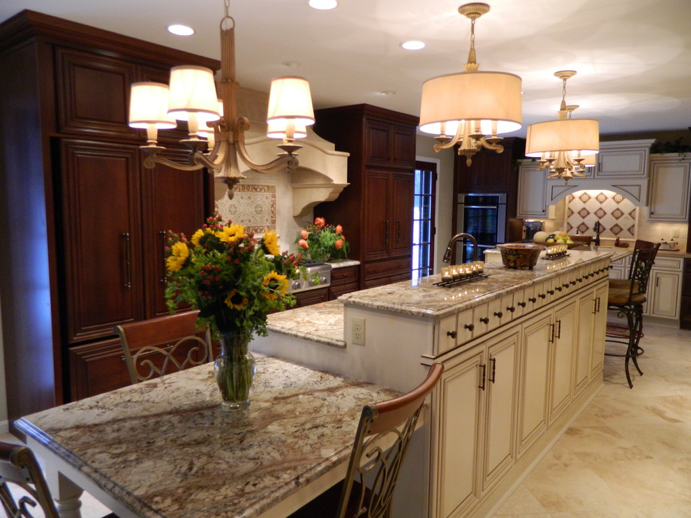 Example of a mid-sized classic galley travertine floor eat-in kitchen design in Other with an undermount sink, raised-panel cabinets, granite countertops, beige backsplash, paneled appliances, stone tile backsplash, an island and dark wood cabinets