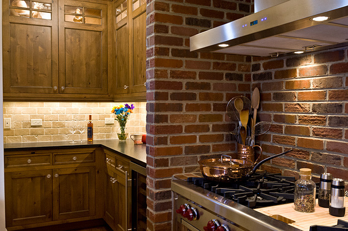 Medelhavsstil inredning av ett mellanstort kök, med en rustik diskho, släta luckor, skåp i mellenmörkt trä, granitbänkskiva, brunt stänkskydd, stänkskydd i stenkakel, rostfria vitvaror, mellanmörkt trägolv och en köksö