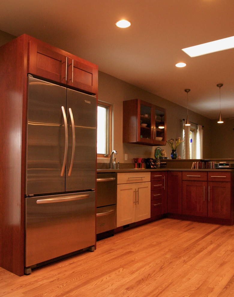 Photo of a modern l-shaped kitchen/diner in Albuquerque with medium wood cabinets, composite countertops, stainless steel appliances, light hardwood flooring, no island and shaker cabinets.