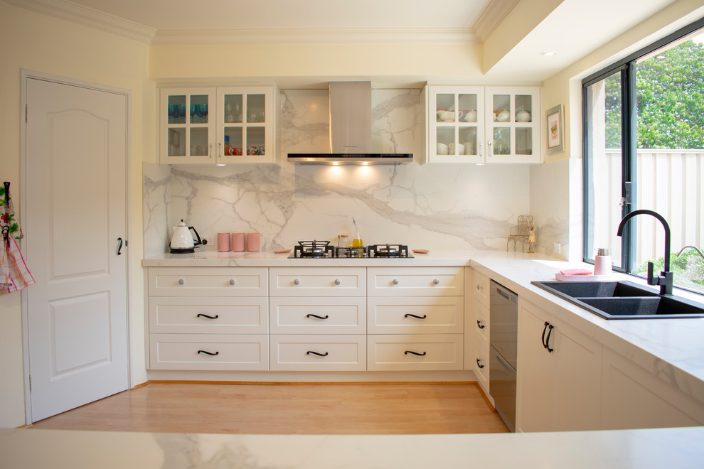 Idéer för att renovera ett mellanstort medelhavsstil vit vitt kök, med en dubbel diskho, skåp i shakerstil, vita skåp, vitt stänkskydd, stänkskydd i sten, rostfria vitvaror, laminatgolv, en halv köksö och brunt golv