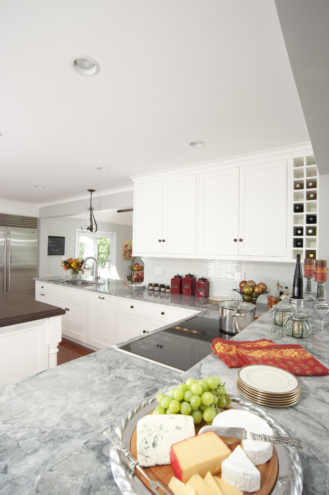 Open concept kitchen - mid-sized traditional l-shaped open concept kitchen idea in Boston with an undermount sink, recessed-panel cabinets, white cabinets, granite countertops, green backsplash, glass tile backsplash, stainless steel appliances and an island