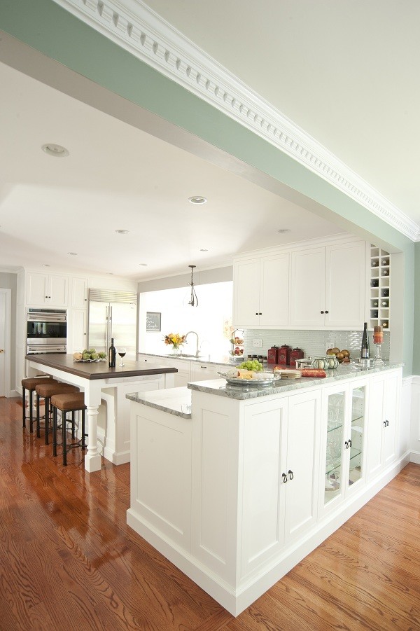 Example of a large classic l-shaped medium tone wood floor open concept kitchen design in Boston with an undermount sink, recessed-panel cabinets, white cabinets, quartzite countertops, green backsplash, glass tile backsplash, stainless steel appliances and an island