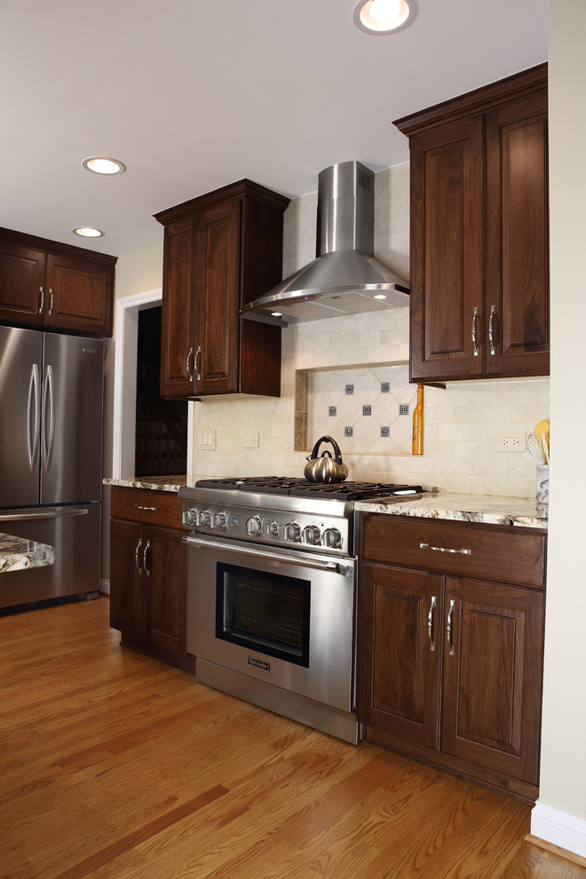 Inspiration for a large transitional l-shaped medium tone wood floor eat-in kitchen remodel in Chicago with an undermount sink, raised-panel cabinets, medium tone wood cabinets, granite countertops, beige backsplash, subway tile backsplash, stainless steel appliances and an island