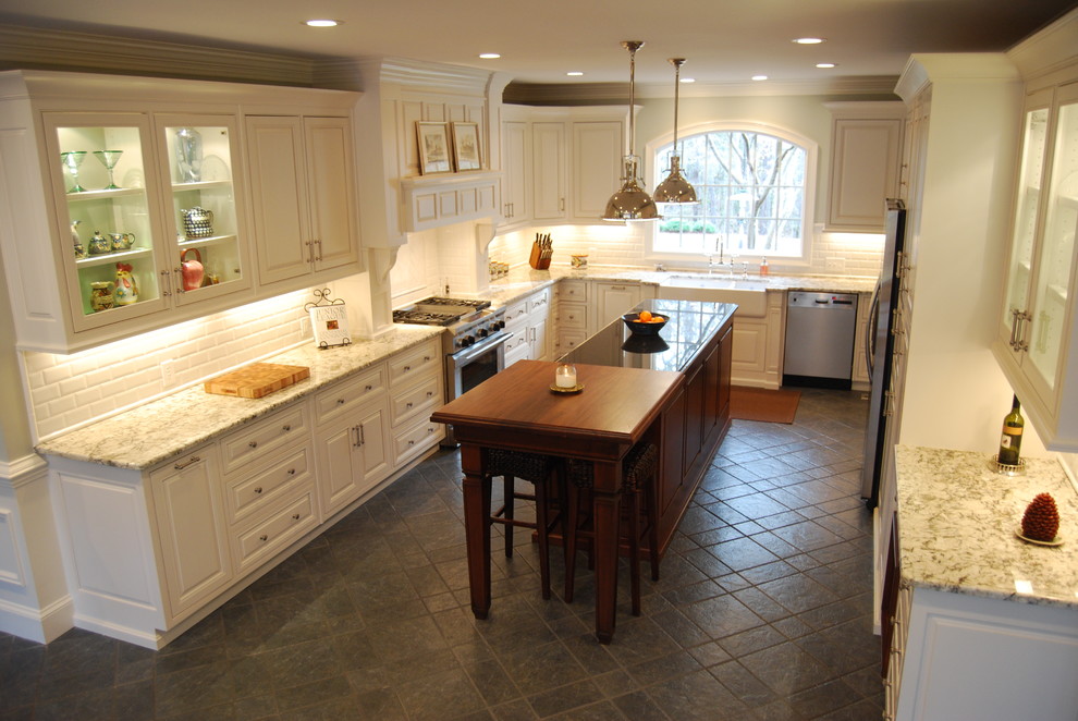 Example of a large classic l-shaped slate floor and gray floor eat-in kitchen design in Atlanta with a farmhouse sink, raised-panel cabinets, white cabinets, granite countertops, white backsplash, subway tile backsplash, stainless steel appliances and an island