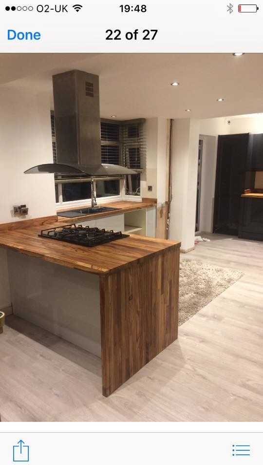 Imagen de cocina contemporánea de tamaño medio con fregadero de doble seno, puertas de armario blancas, encimera de madera, electrodomésticos negros, suelo laminado y península