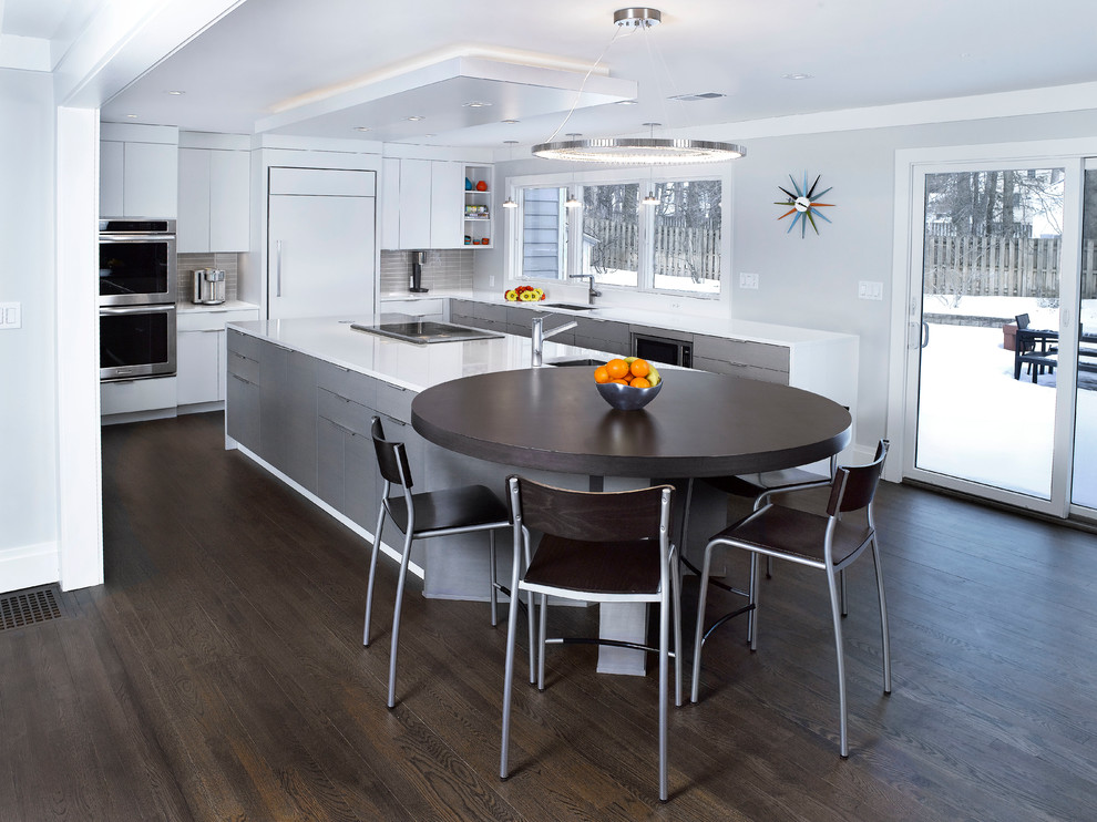 Mittelgroße Moderne Küche in L-Form mit flächenbündigen Schrankfronten, weißen Schränken, Küchenrückwand in Grau, Rückwand aus Glasfliesen, Küchengeräten aus Edelstahl, braunem Holzboden und Kücheninsel in New York