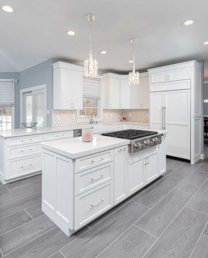 Inspiration for a transitional porcelain tile and gray floor kitchen remodel in Philadelphia with a farmhouse sink, shaker cabinets, white cabinets, quartzite countertops, ceramic backsplash, paneled appliances, an island and white countertops