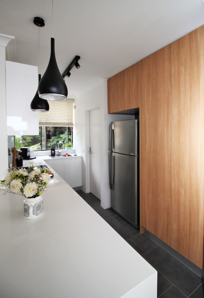 This is an example of a medium sized scandi u-shaped kitchen/diner in Sydney with a single-bowl sink, flat-panel cabinets, white cabinets, quartz worktops, white splashback, glass sheet splashback, stainless steel appliances, porcelain flooring and no island.