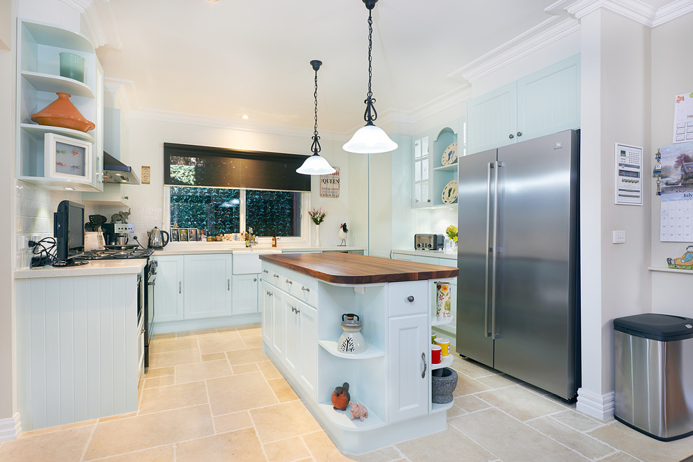 Example of a mid-sized classic u-shaped ceramic tile open concept kitchen design in Melbourne with a farmhouse sink, shaker cabinets, green cabinets, wood countertops, beige backsplash, ceramic backsplash, black appliances and an island