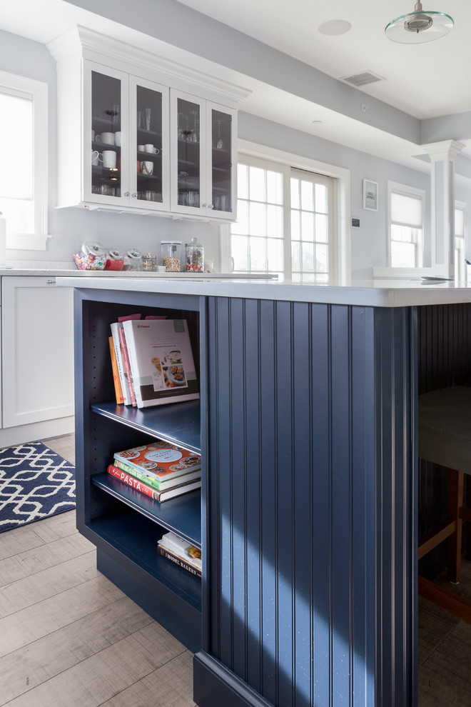 Inspiration for a mid-sized transitional u-shaped medium tone wood floor eat-in kitchen remodel in Boston with an undermount sink, shaker cabinets, white cabinets, solid surface countertops, blue backsplash, glass tile backsplash, stainless steel appliances and an island
