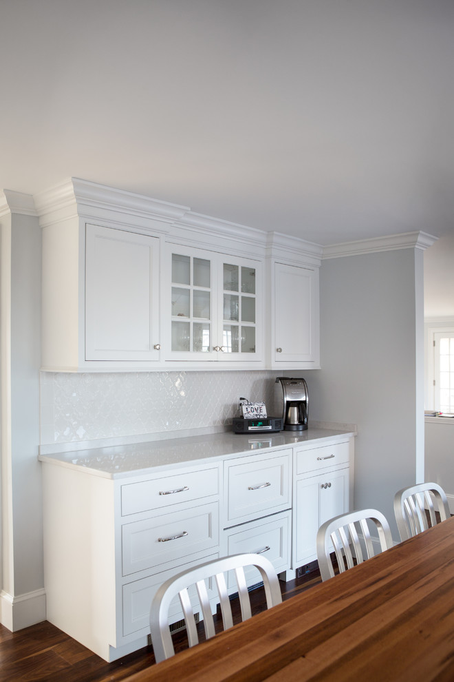 This is an example of a medium sized classic l-shaped kitchen pantry in Boston with a submerged sink, flat-panel cabinets, white cabinets, wood worktops, white splashback, ceramic splashback, stainless steel appliances, dark hardwood flooring and an island.