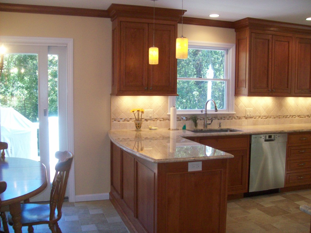 Klassisk inredning av ett mellanstort kök, med en undermonterad diskho, luckor med infälld panel, skåp i mellenmörkt trä, granitbänkskiva, beige stänkskydd, stänkskydd i stenkakel, rostfria vitvaror, travertin golv och en halv köksö