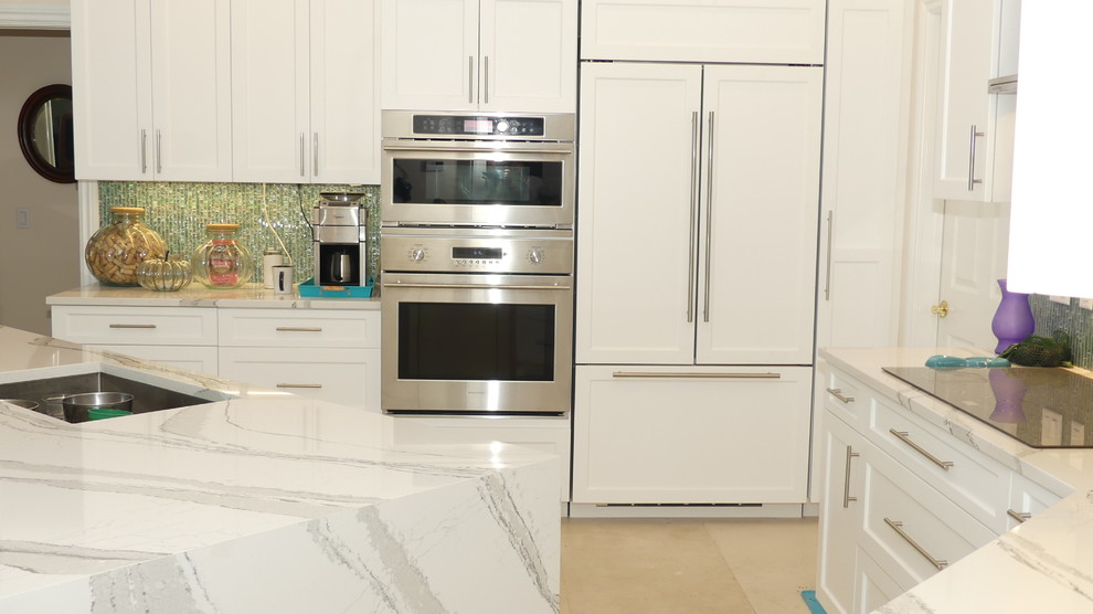 Medium sized contemporary u-shaped open plan kitchen in Miami with a submerged sink, shaker cabinets, white cabinets, engineered stone countertops, green splashback, glass tiled splashback, stainless steel appliances, concrete flooring, an island, beige floors and white worktops.