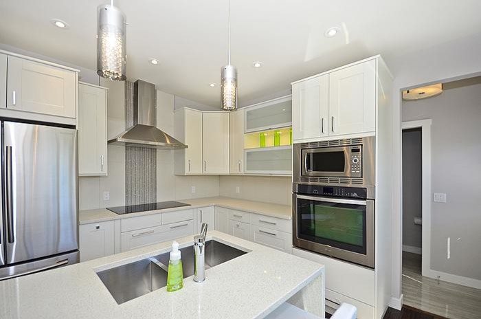 Example of a mid-sized trendy l-shaped medium tone wood floor eat-in kitchen design in Calgary with an undermount sink, shaker cabinets, white cabinets, quartzite countertops, white backsplash, porcelain backsplash, stainless steel appliances and an island