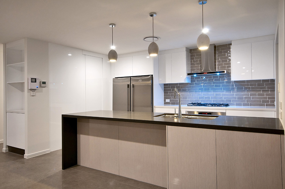 Inspiration for a mid-sized modern galley porcelain tile eat-in kitchen remodel in Gold Coast - Tweed with an undermount sink, light wood cabinets, quartz countertops, beige backsplash, subway tile backsplash, stainless steel appliances and a peninsula